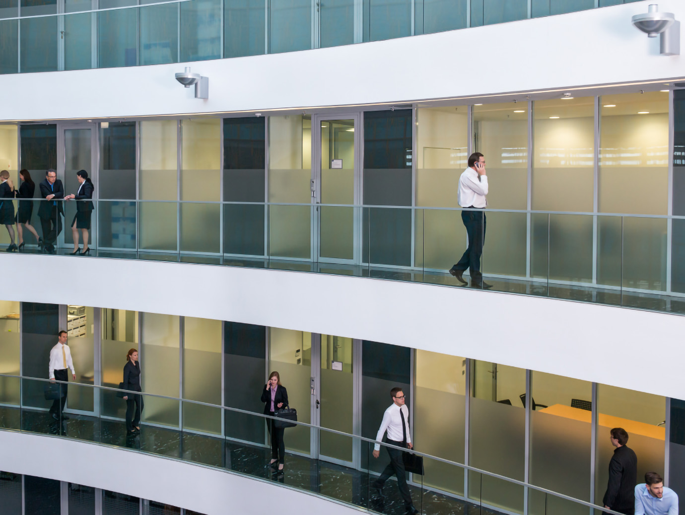 Group of people walking on the balcony in different floors of an office building