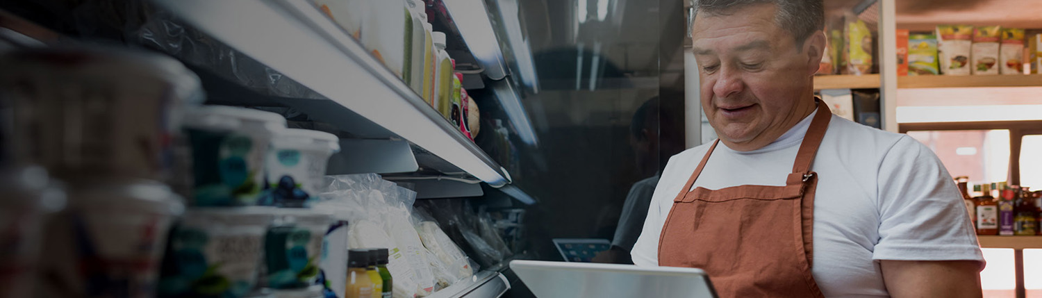 Man in apron using a tablet to take stock in a supermarket