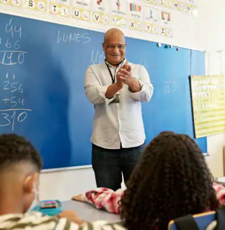 A teacher applauding a student in a classroom