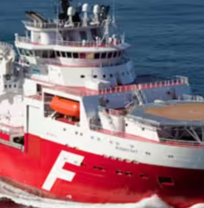 A red ship with a helipad sailing in the ocean