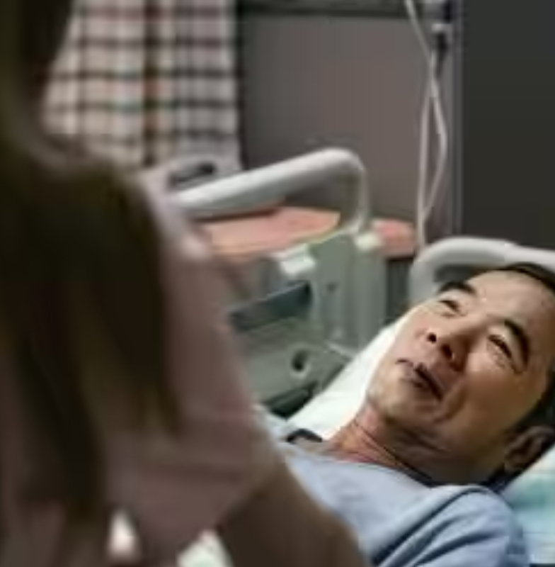 An elderly patient lying in bed, smiling at a nurse