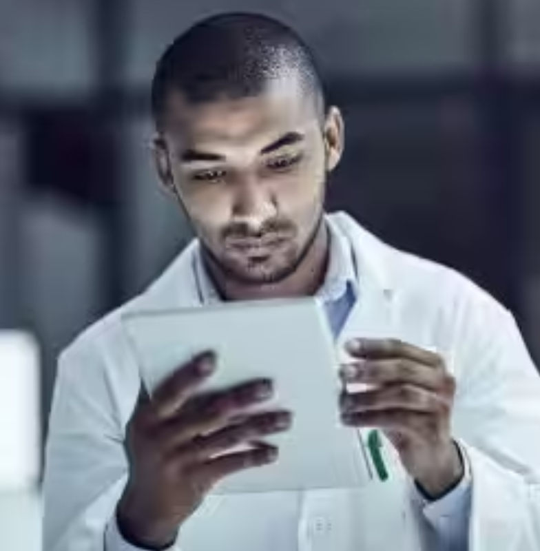 A researcher seated near a microscope, examining a tablet