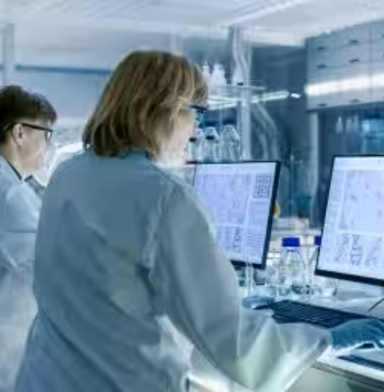 Medical researchers in a lab, looking at images of cells and DNA on computers