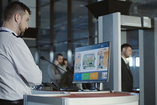 A security employee watching baggage scan footage on a monitor