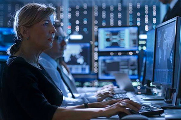 Man and woman working at their desktops in a server room