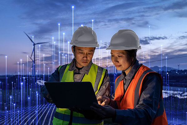 Two technicians wearing safety gear and looking at a laptop in a wind farm, surrounded by OpenBlue graphics 